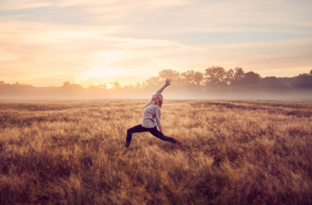 Frau im Feld macht Anusara Yoga