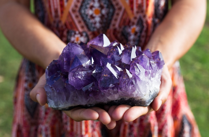 Frau hält lila Amethyst Kristall