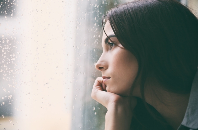 Frau schaut depressiv aus dem Fenster