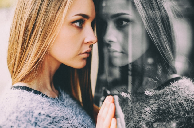 Frau sieht ihr Spiegelbild im Fenster
