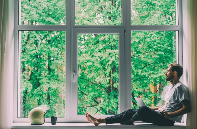 mann sitzt am fenster und sucht soziale kontakte