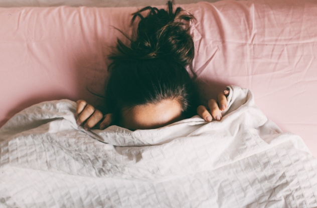 Frau versteckt sich vor Scham unter der Decke