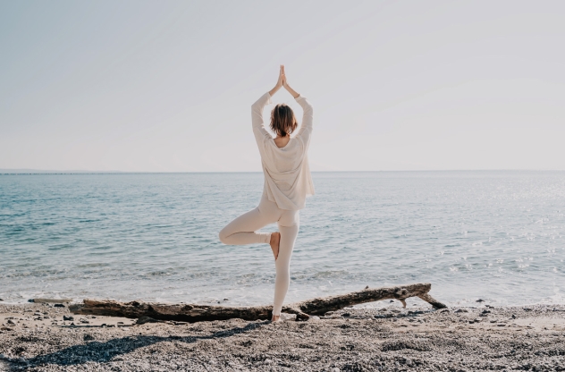 Wurzelchakra öffnen Frau macht Yoga Baum am Strand
