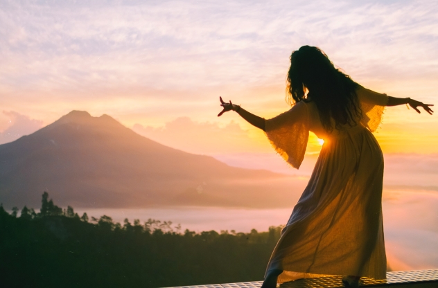 Frau macht Sakralchakra-Übung bei Sonnenuntergang