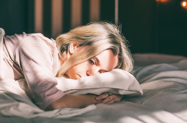 Traurigkeit überwinden: Frau liegt traurig im Bett