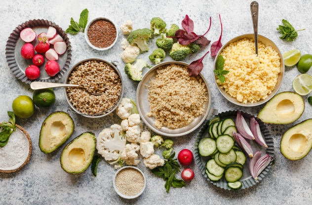 Verschiedene Lebensmittel, darunter Avocados, Radieschen, Hafer, Blumenkohl und Quinoa, sind auf einer Platte angerichtet.