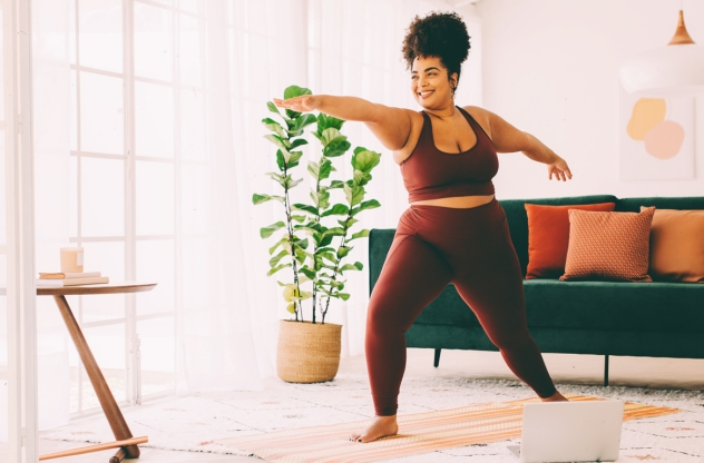 Frau macht Yoga gegen Stress Zuhause und ist im Krieger 2