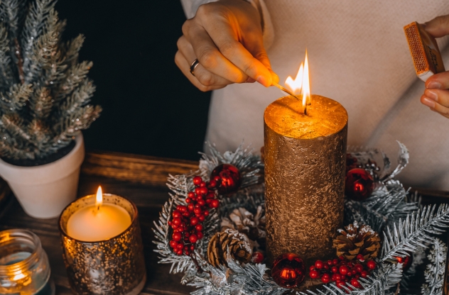 Frau zündet Adventskerze an für mehr Achtsamkeit im Advent: Finde Rituale und Übungen für eine besinnliche Vorweihnachtszeit