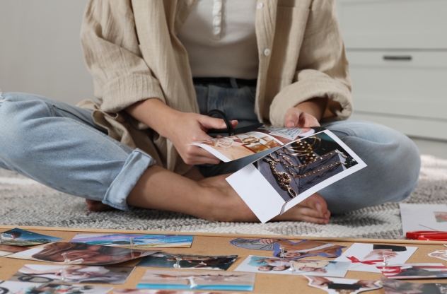 Frau erstellt sich ihr persönliches Vision Board und schneidet Bilder aus