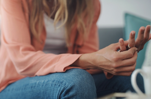 Eine Frau sitzt auf dem Sofa und dreht nervös an ihrem Ring | Nervosität und innere Unruhe bekämpfen
