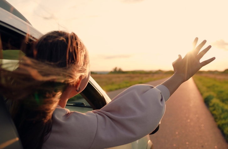 Frau in Auto mit ausgestrecktem Arm