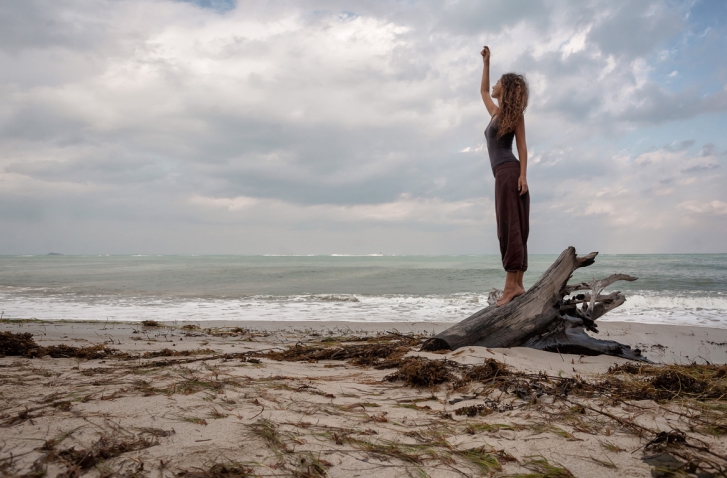 Frau am Strand mit zum Himmel gestreckter Hand