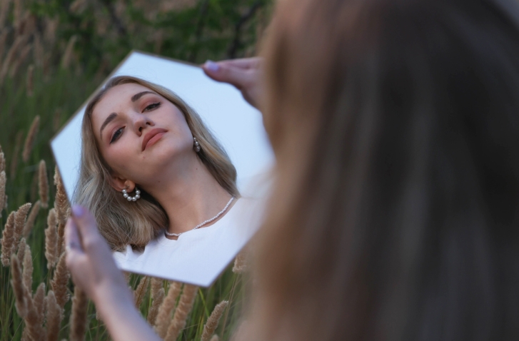 Frau, die in einen Spiegel blickt