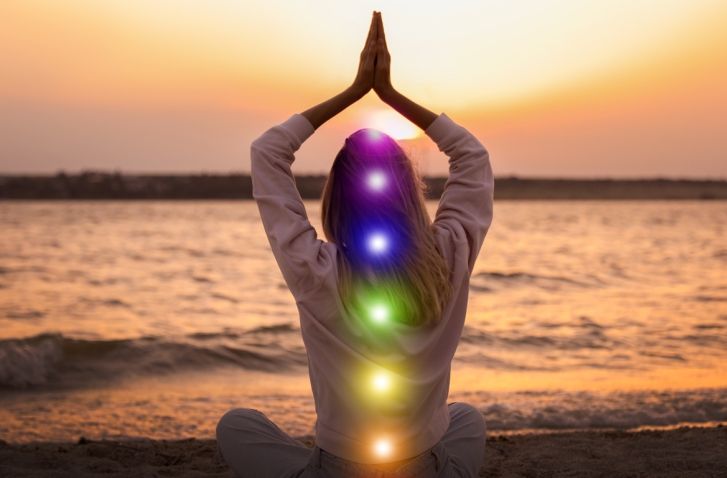 Frau mit gefalteten Händen über dem Kopf und farbigen Flecken entlang der Wirbelsäule