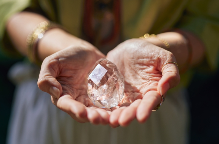 Durchsichtiger Kristall in zu Schale geformten Händen