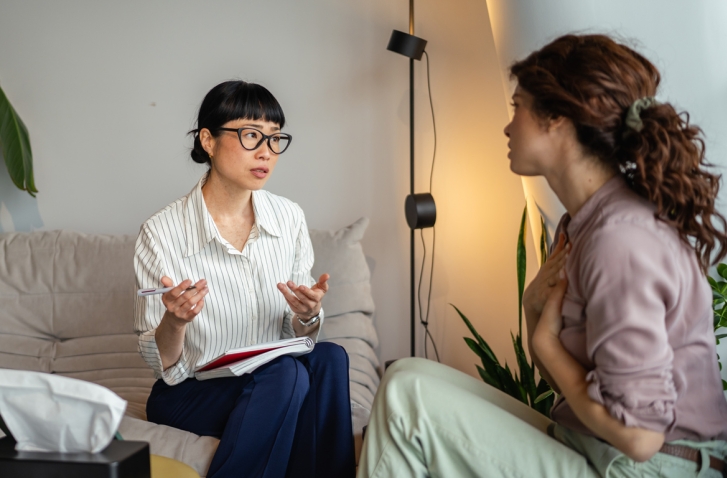 Zwei Frauen die gegenüber einander sitzen und sich unterhalten und gestikulieren