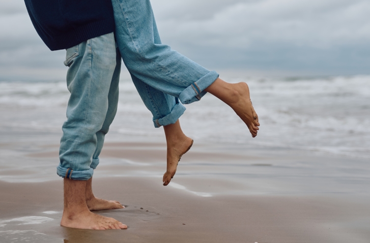 Liebe im Buddhismus: Eine Person hebt im Sand eine andere Person im Sprung hoch.