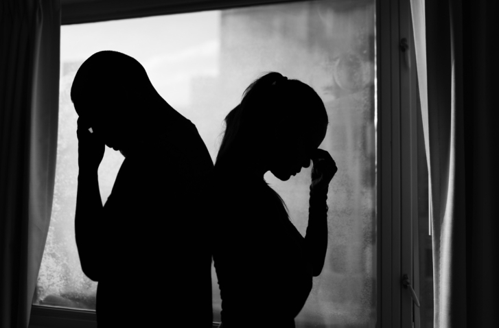 Mann und Frau die Rücken an Rücken stehen mit dem Gesicht auf der Hand abgestützt