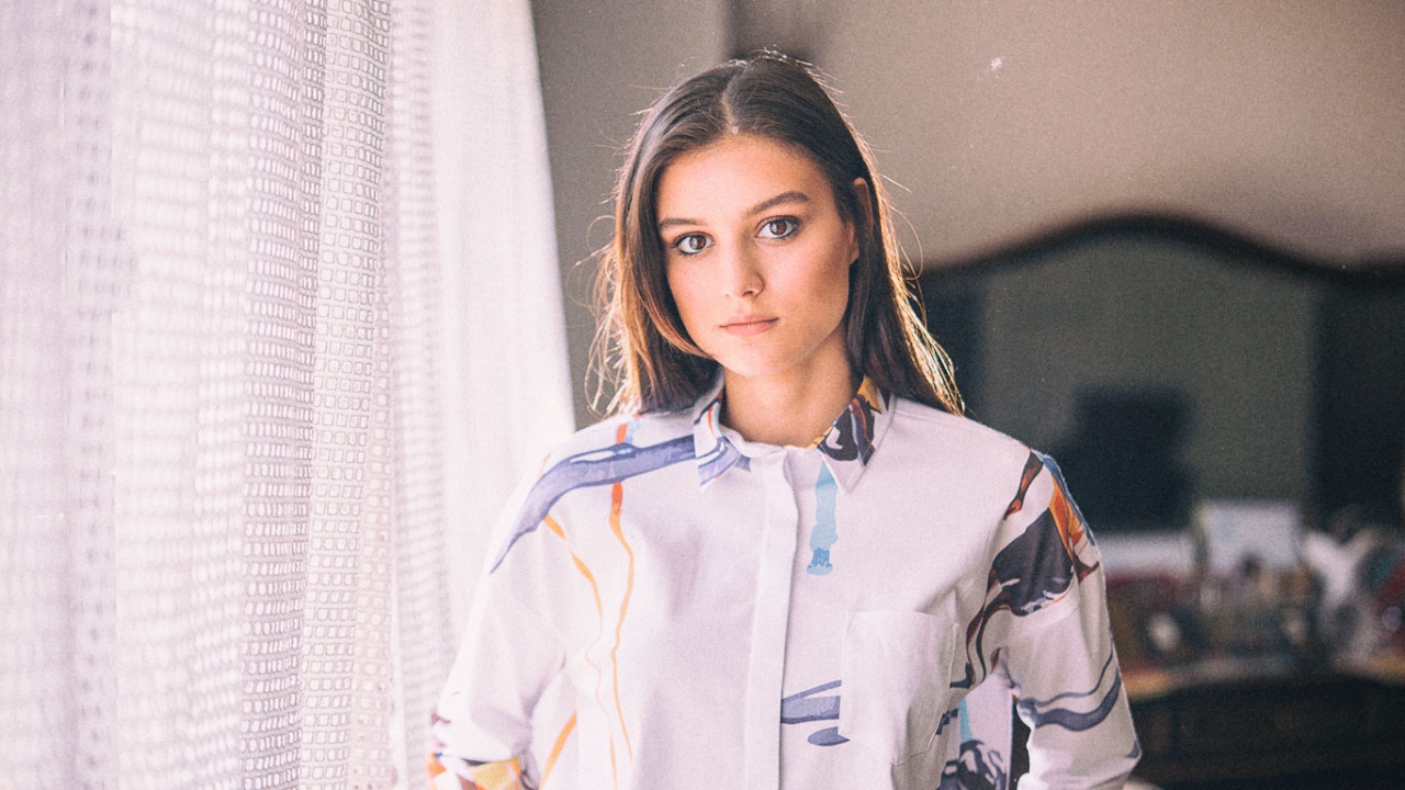 Eine junge Frau mit langen Haaren blickt ruhig in die Kamera | Erschöpfung vorbeugen