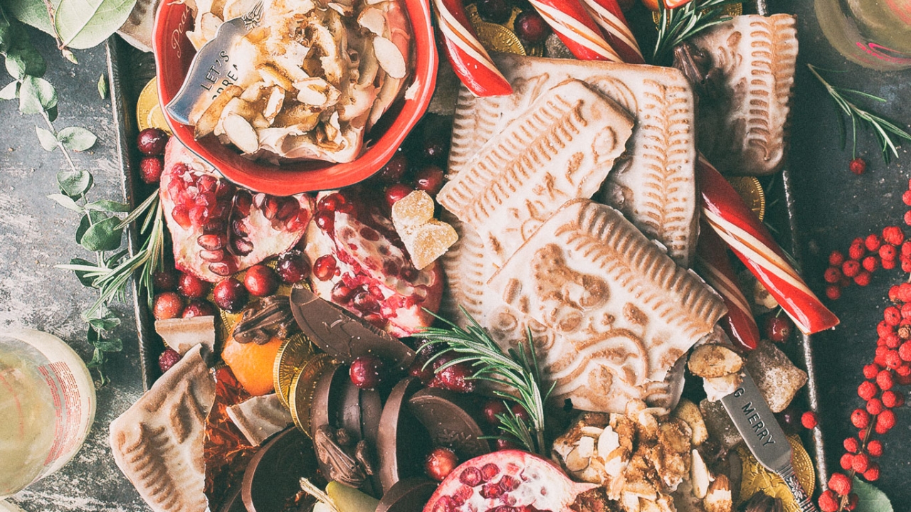 Vegane Weihnachten: Gesundes Weihnachtsgebäck Ein festlich angerichtetes Tablett mit Spekulatius, Schokolade, Nüssen, Granatapfel, kandierten Früchten und Zuckerstangen.