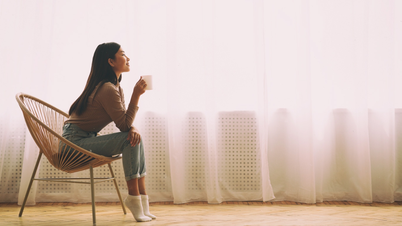Fastenzeit Ideen: Eine Frau genießt einen Kaffee in einem Rattansessel
