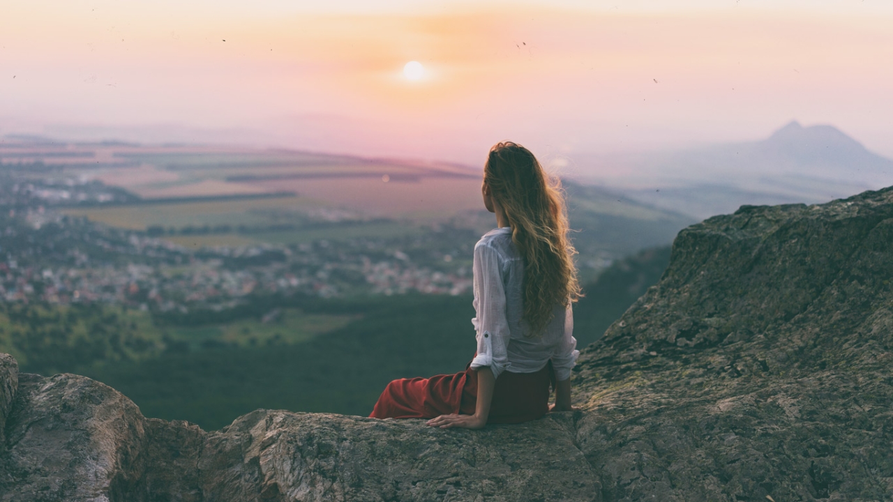 Ja zum Leben Eine Frau sitzt auf einem Vorsprung und schaut ins Tal