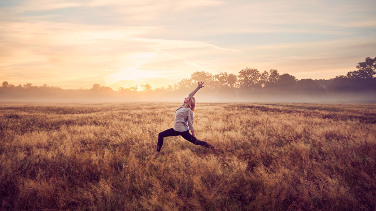Frau im Feld macht Anusara Yoga