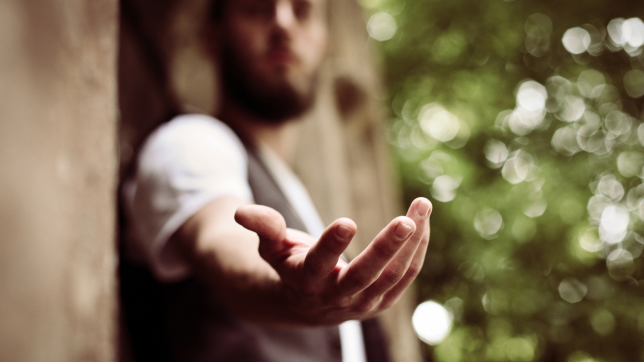 Mann streckt helfend seine Hand aus