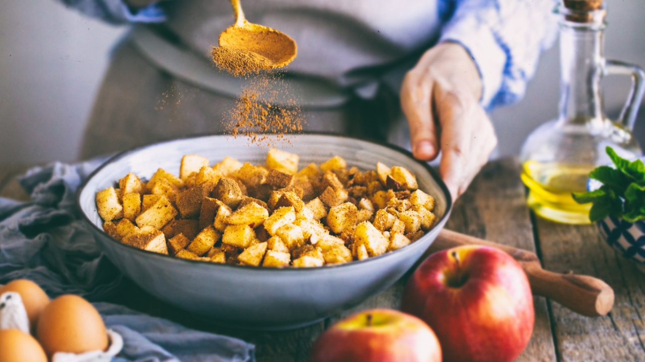 Frau bestäubt Apfelstücke mit Zimt