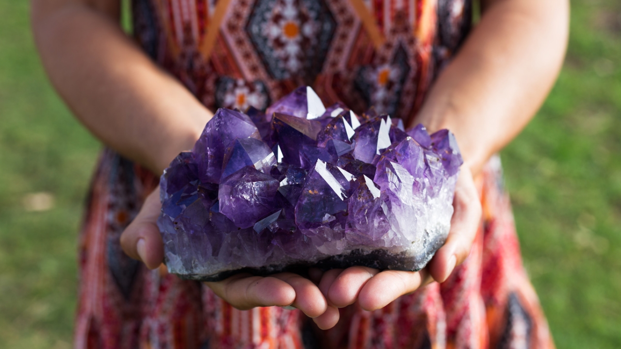 Frau hält lila Amethyst Kristall Frau hält lila Amethyst Kristall