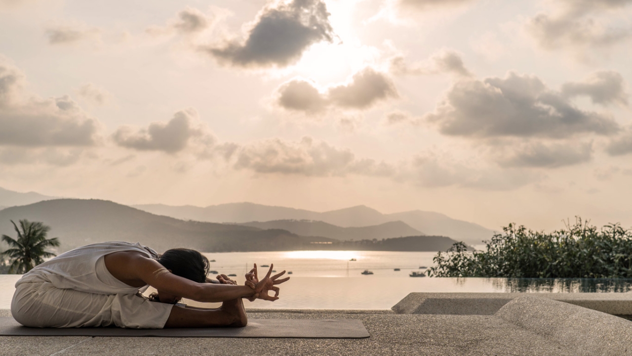 Frau macht Yoga-Vorbeuge am Meer Frau macht Yoga-Vorbeuge am Meer