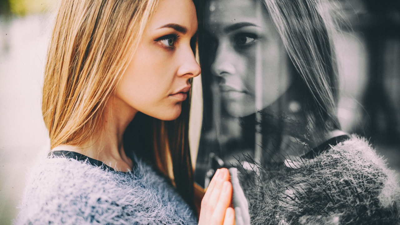 Frau sieht ihr Spiegelbild im Fenster