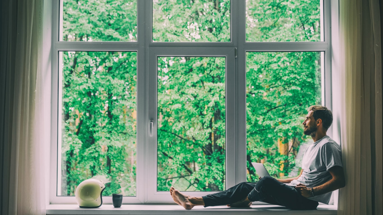 mann sitzt am fenster und sucht soziale kontakte
