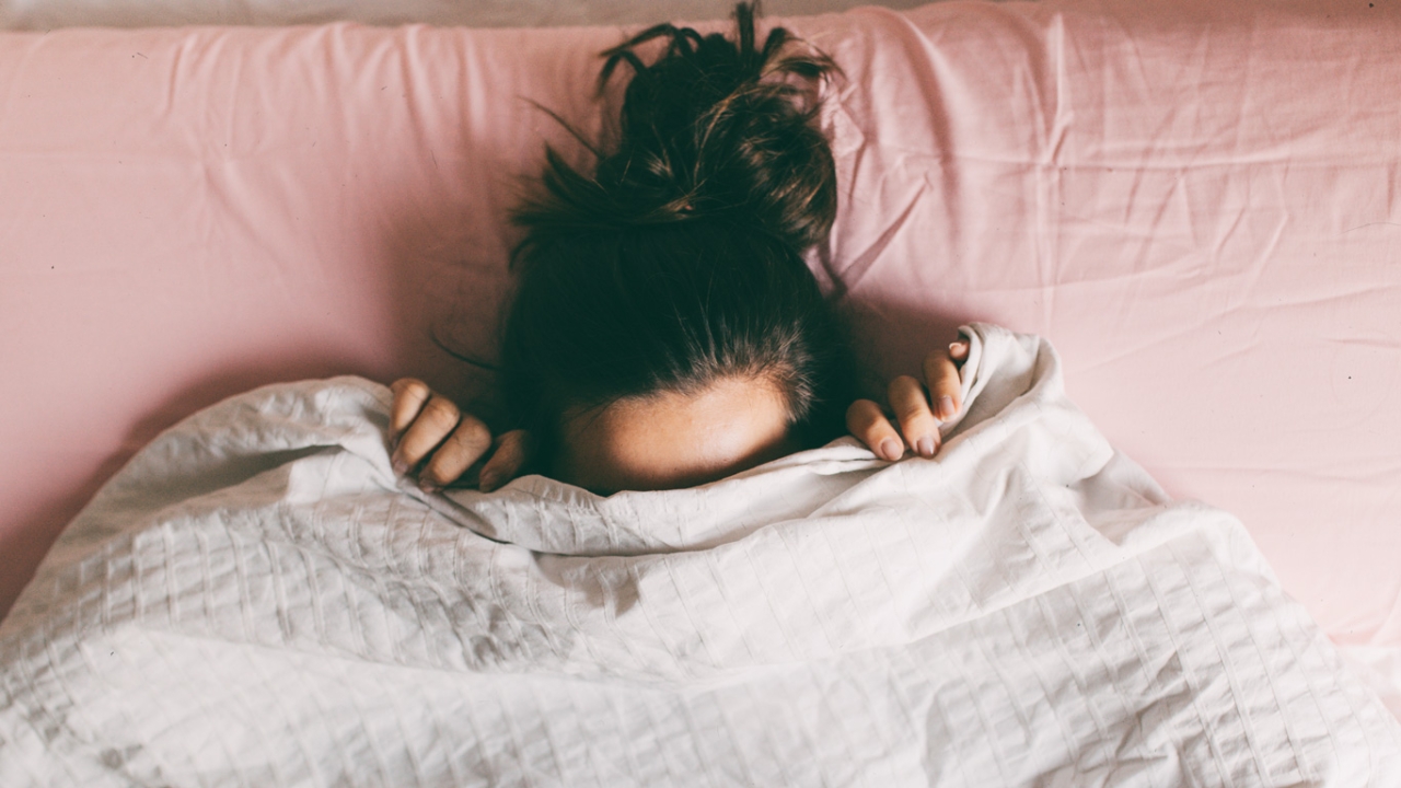 Frau versteckt sich vor Scham unter der Decke