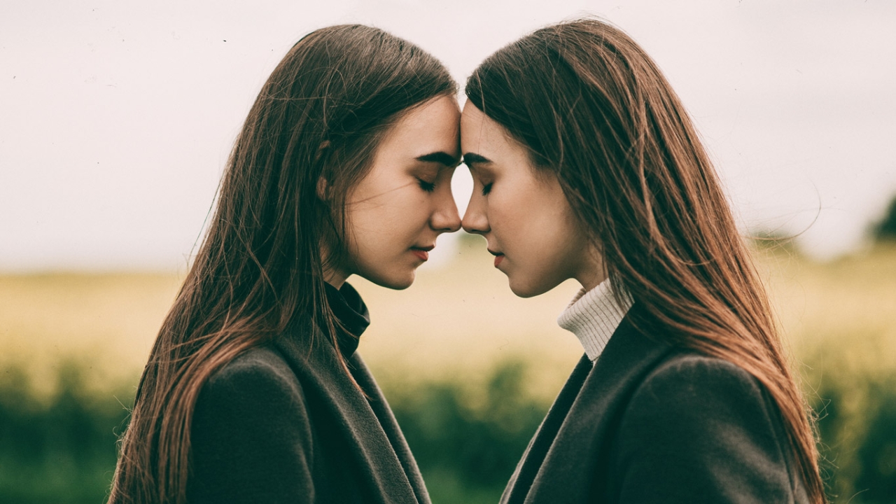 Zwei Frauen lehnen sich mit der Stirn aneinander