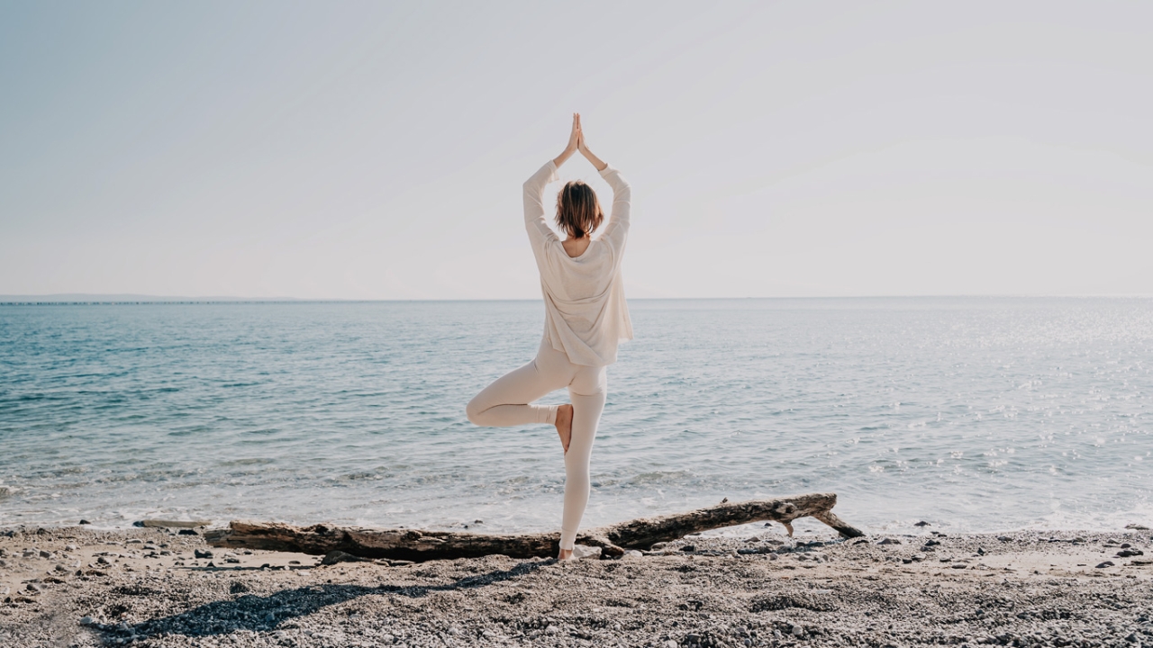 Wurzelchakra öffnen Frau macht Yoga Baum am Strand