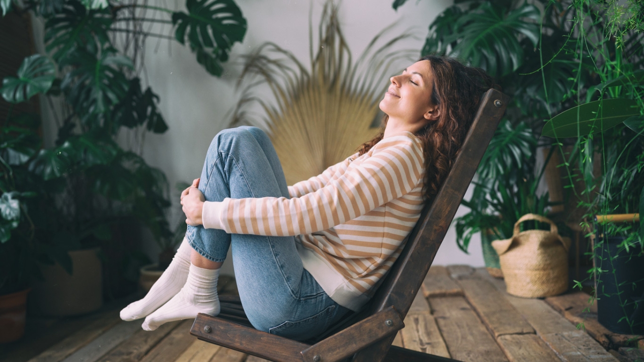 Manifestieren: Frau sitzt glücklich auf Stuhl