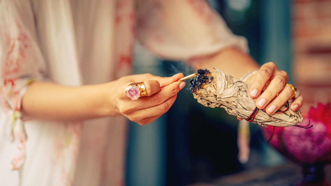 Frau räuchert Wohnung mit Salbeizweig Frau räuchert Wohnung mit Salbeizweig