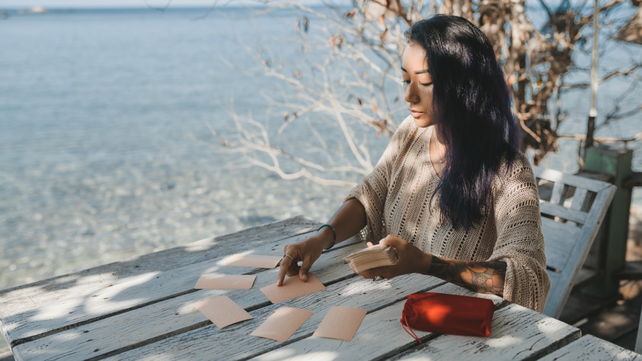 Frau legt Tarot-Karten am Meer Frau legt Tarot-Karten am Meer
