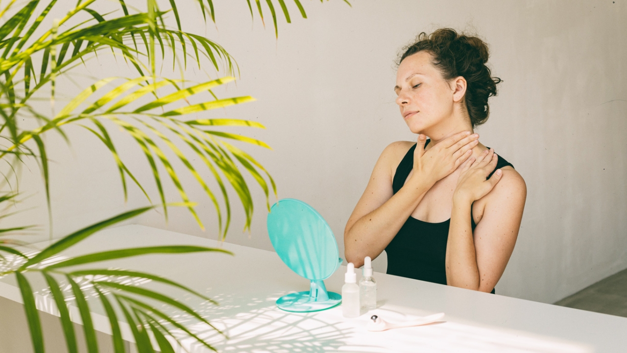 Frau sitzt vor Spiegel und macht Face-Yoga