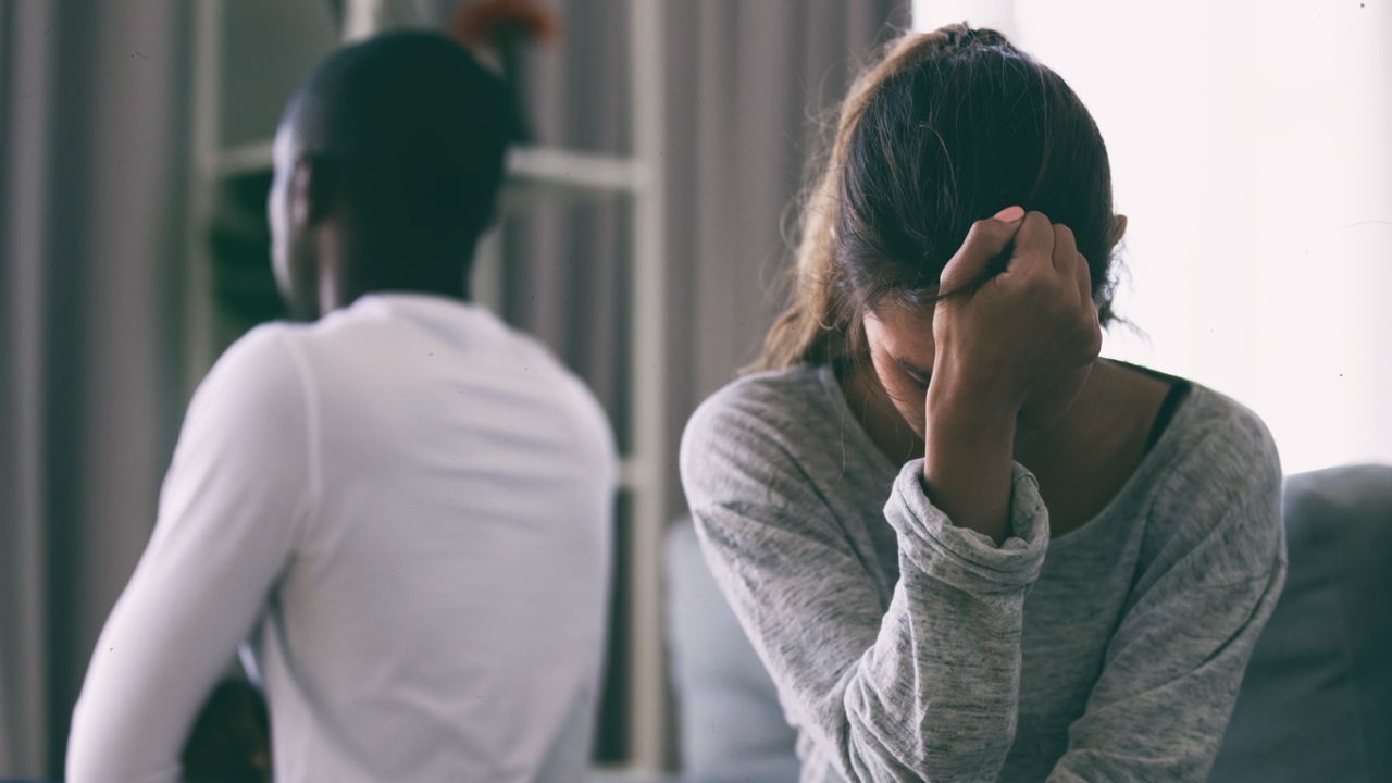 Mann und Frau sitzen mit dem Rücken zueinander und haben ein Missverständnis