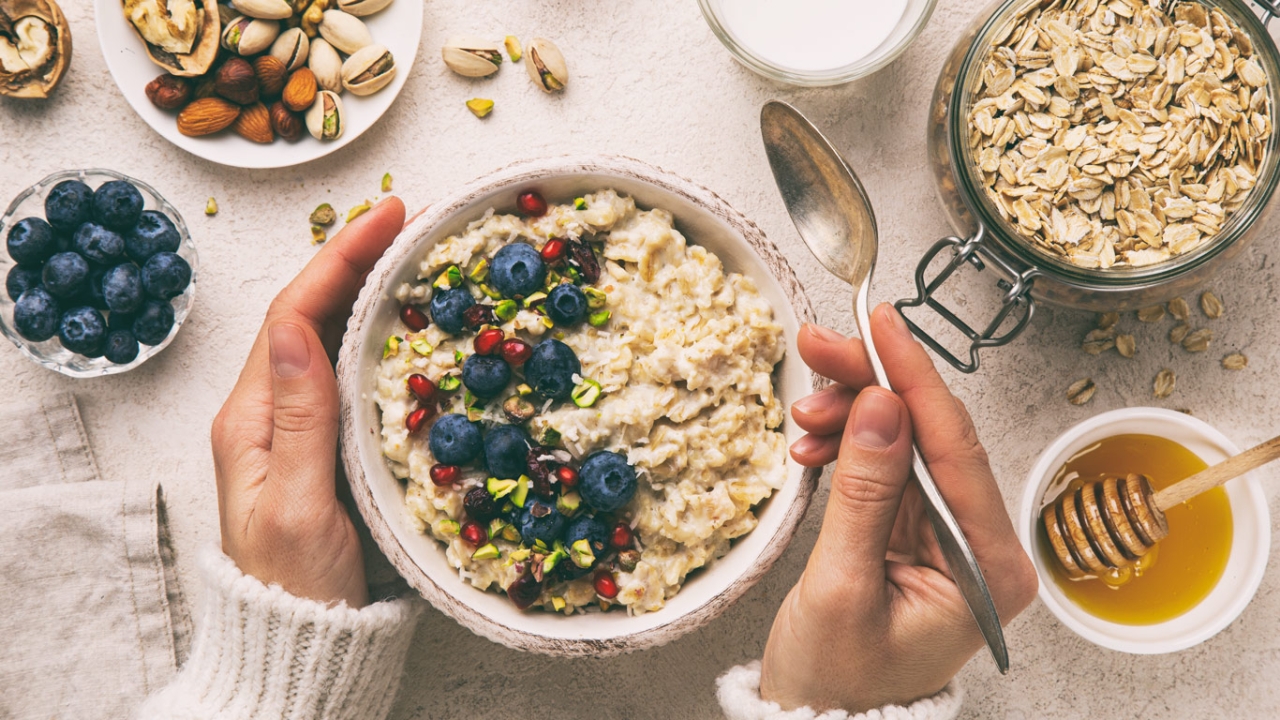 Blick von oben auf eine Schale mit Müsli und Beeren. Weitere Zutaten liegen verstreut im Bild.