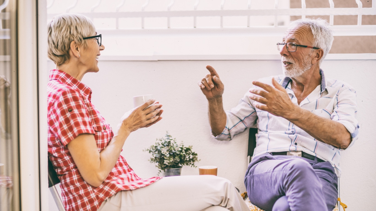 Älteres Paar sitzt auf Balkon und sie hören sich aktiv zu