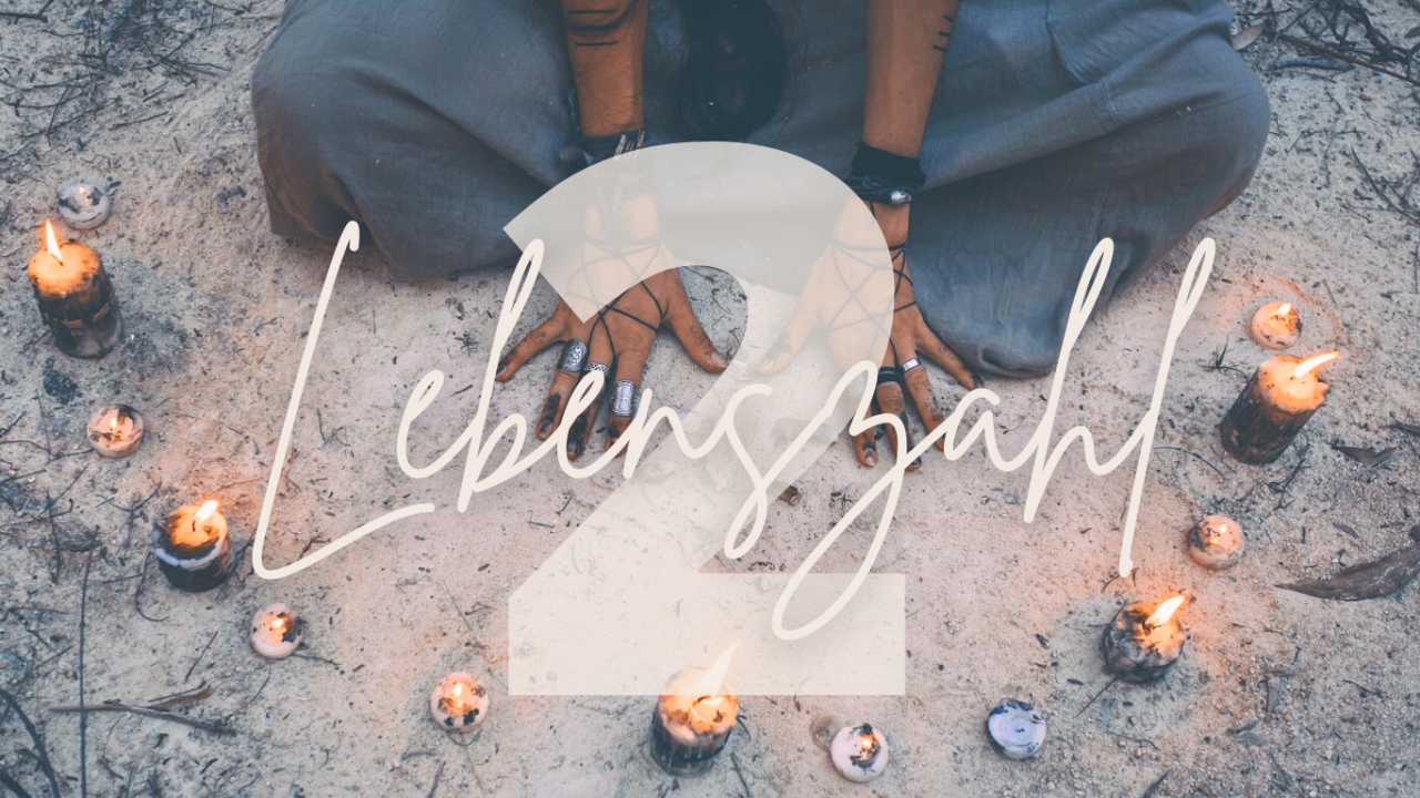 Lebenszahl 2 Lebenszahl 2: Eine große zwei steht vor einem Hintergrund, indem Kerzen in einem Halbkreis aufgestellt sind und eine Person im Schneidersitz die Hände auf dem Boden legt