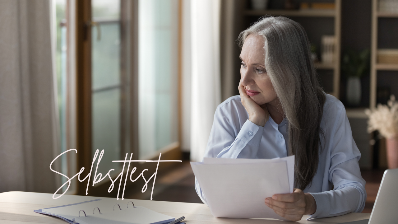 Teaserbild: Hochstapler-Syndrom-Test - Ältere Frau guckt verunsichert an ihrem Schreibtisch