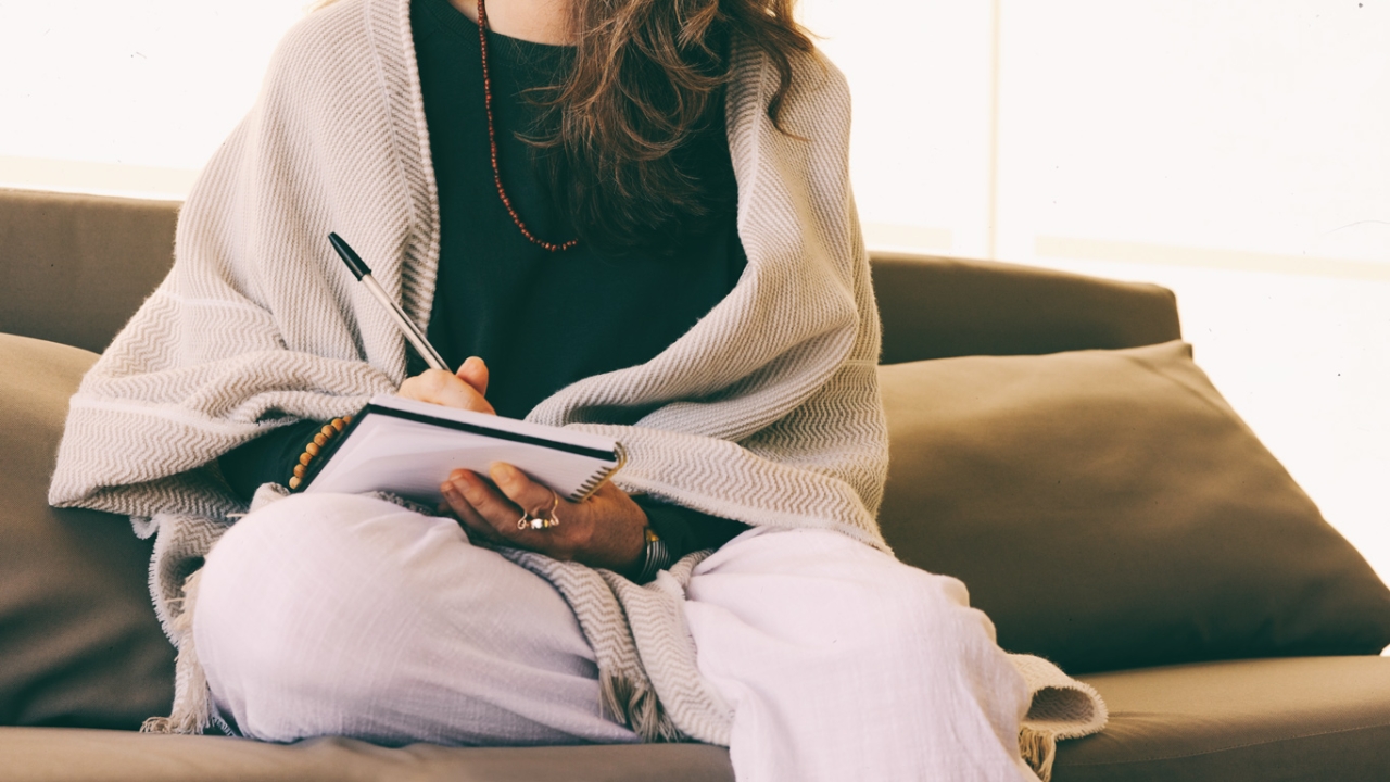 Erfolgsjournal Frau sitzt in legerer Kleidung auf Sofa und schreibt in ihrem Tagebuch Erfolgsjournal: Frau sitzt in legerer Kleidung auf Sofa und schreibt in ihrem Tagebuch