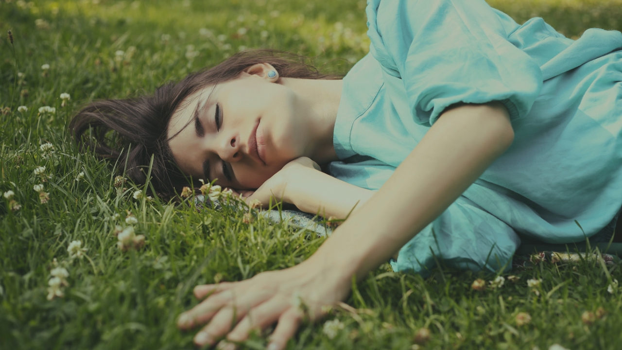 Eine Frau schläft auf dem Gras.