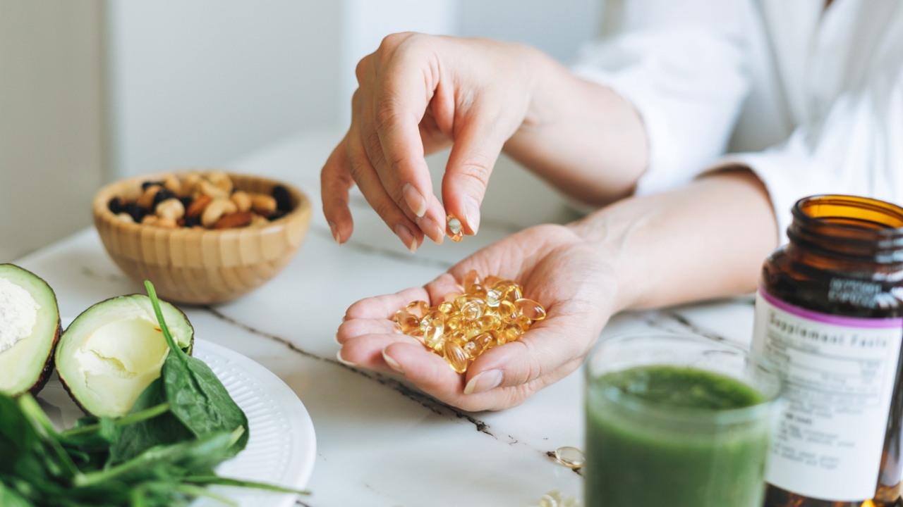 In einer Hand befinden sich Nahrungsergänzungskapseln.