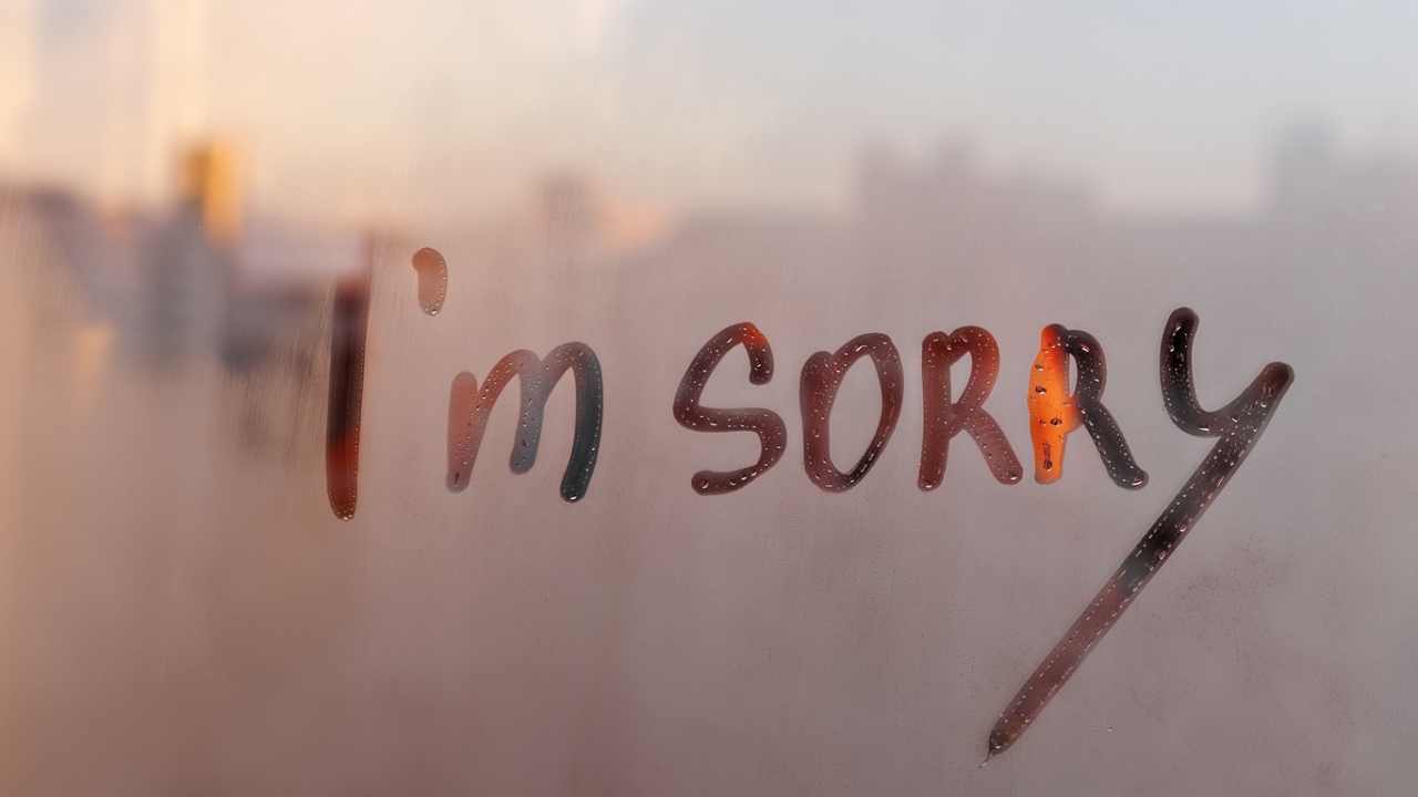 Das Bild zeigt die Worte &quot;I'm Sorry&quot; in großen, handgeschriebenen Buchstaben auf einer beschlagenen Fensterscheibe.