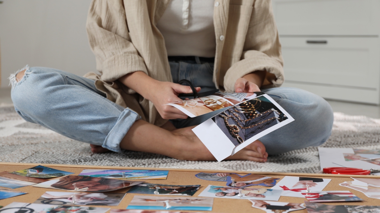 Frau erstellt sich ihr persönliches Vision Board und schneidet Bilder aus Frau erstellt sich ihr persönliches Vision Board und schneidet Bilder aus